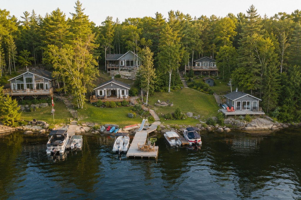 Aerial view of lakeside cottages, docks, and boats on a shared family compound