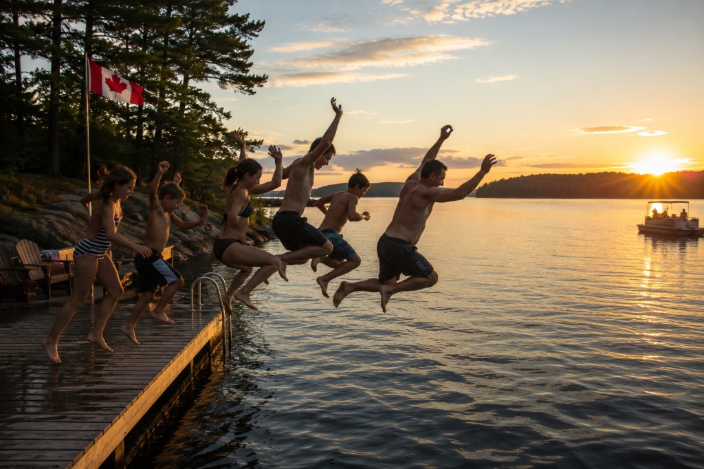 Family jumping off the dock at sunset on the lake